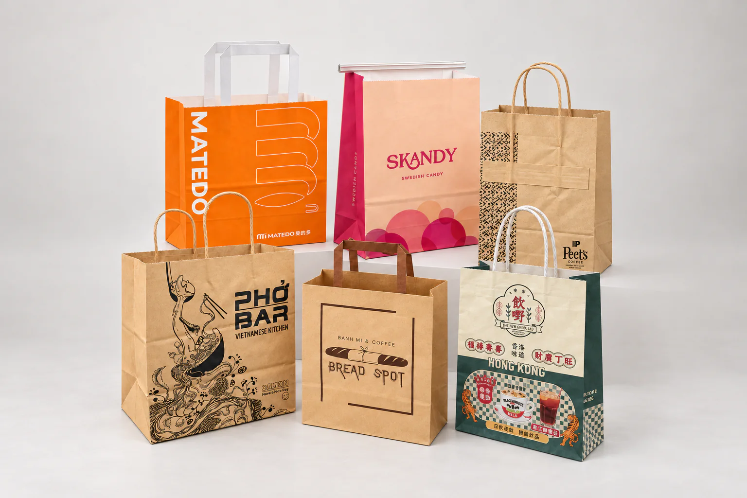 A group of printed and natural kraft takeaway bags in different sizes and carrying styles.