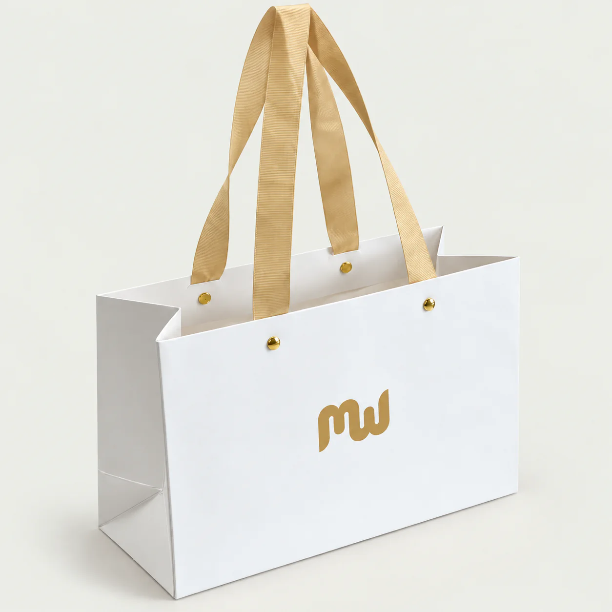 White paper bag with gold ribbon handles fixed by visible metal rivets.