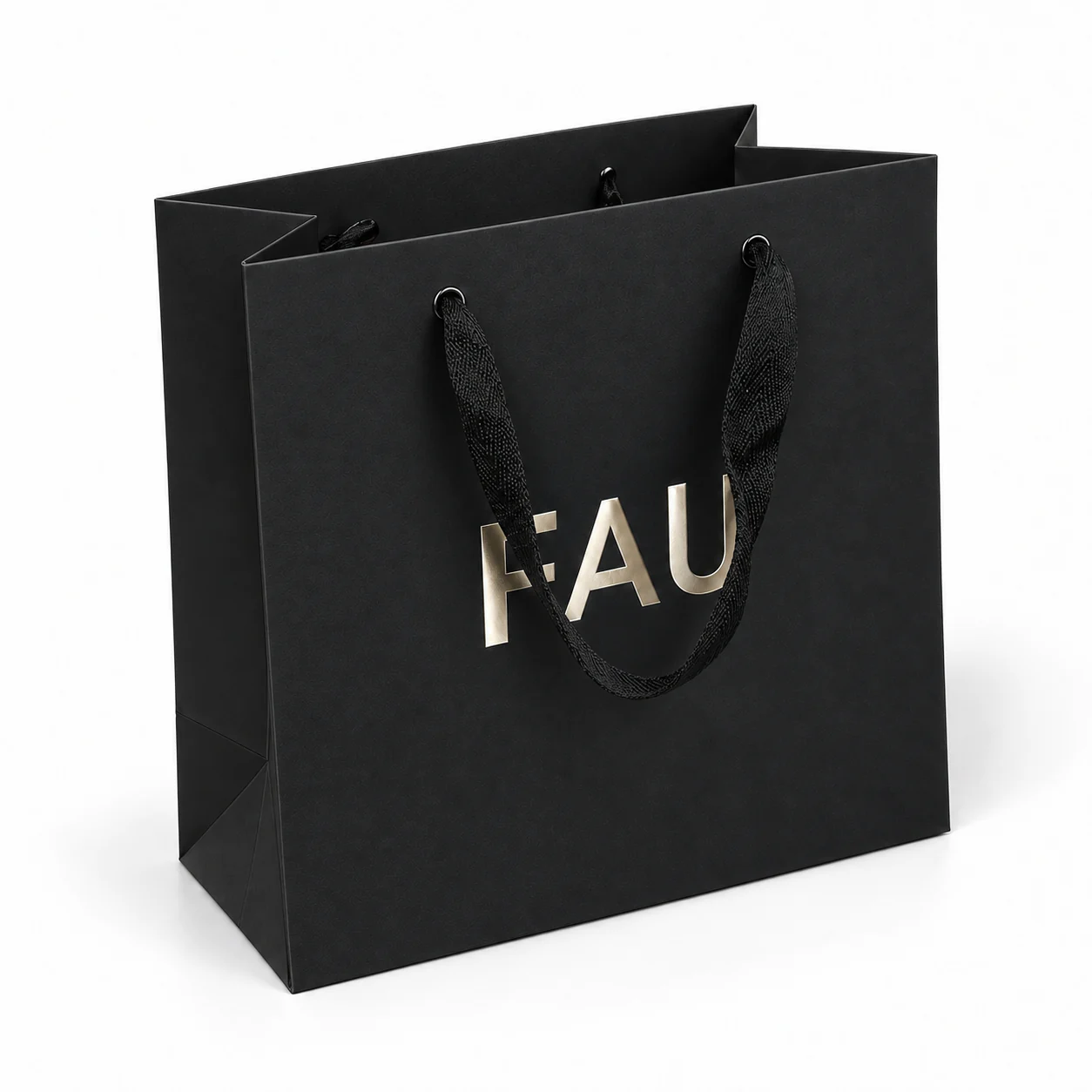 Three-quarter view of a black paper bag with black woven ribbon handles threaded through metal eyelets.