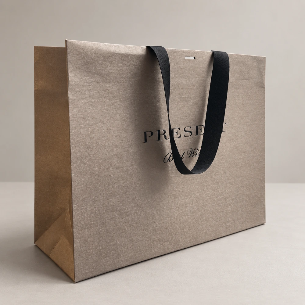 Taupe paper bag with fine surface texture, a draped black ribbon handle and dark lettering partly covered by the ribbon