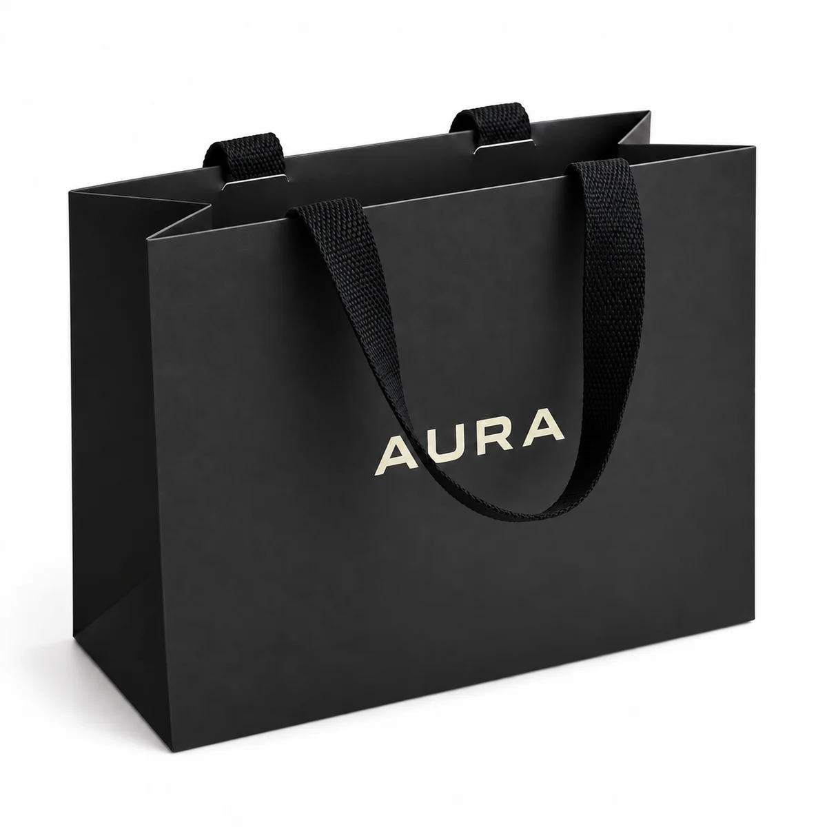 Black paper shopping bag with black ribbon handles and a light-coloured AURA logo.