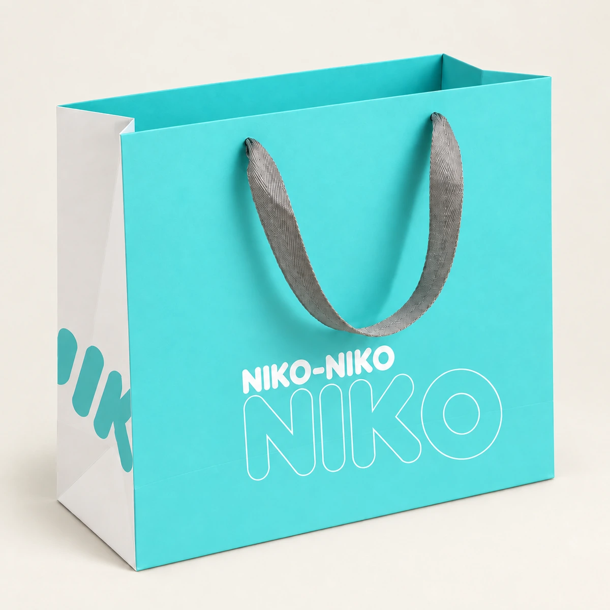 Turquoise paper bag with gray ribbon handles and white printed lettering