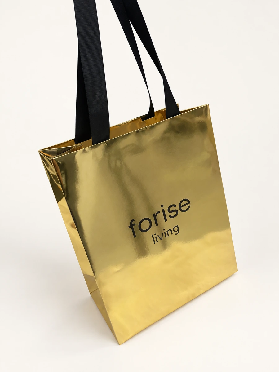 Angled gold forise living paper bag with black lettering and broad black handles extending beyond the top of the frame