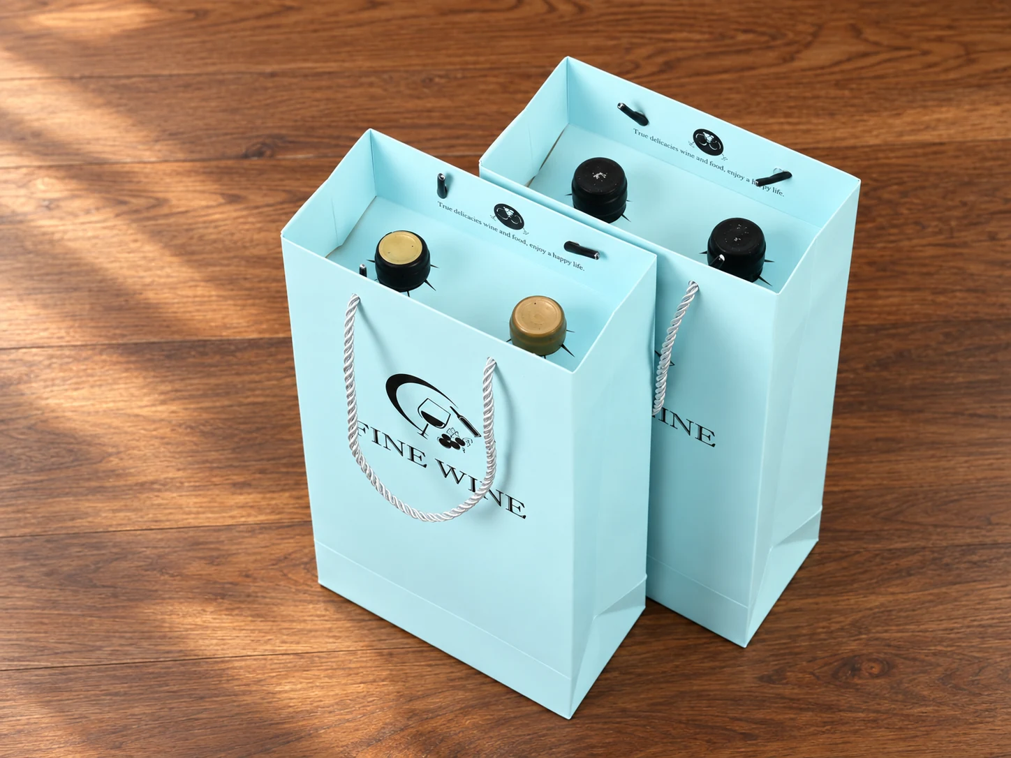 Light blue wine paper bags with two bottle necks held in separate openings in matching card inserts.