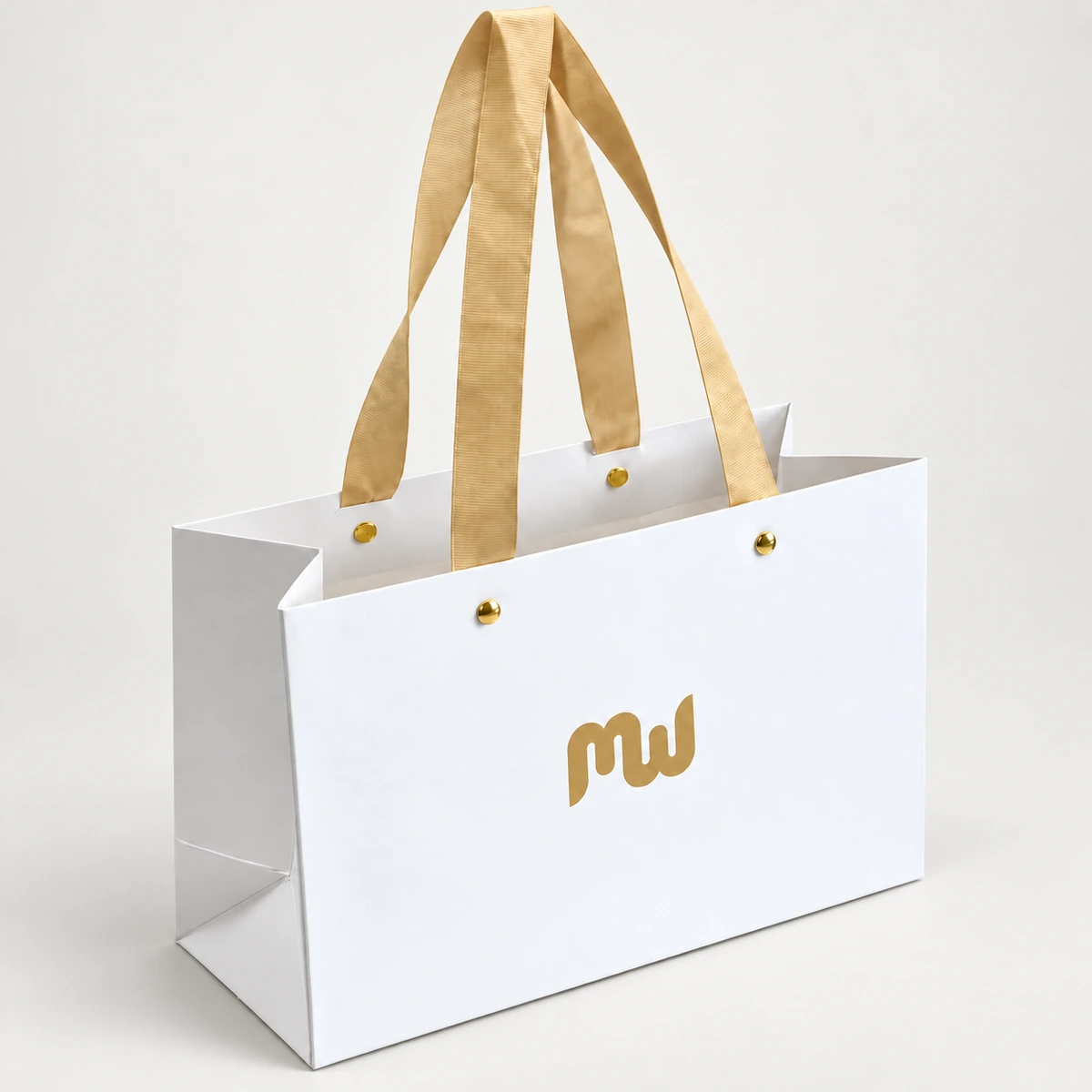 White paper bag with long gold-colored handles and visible rivets