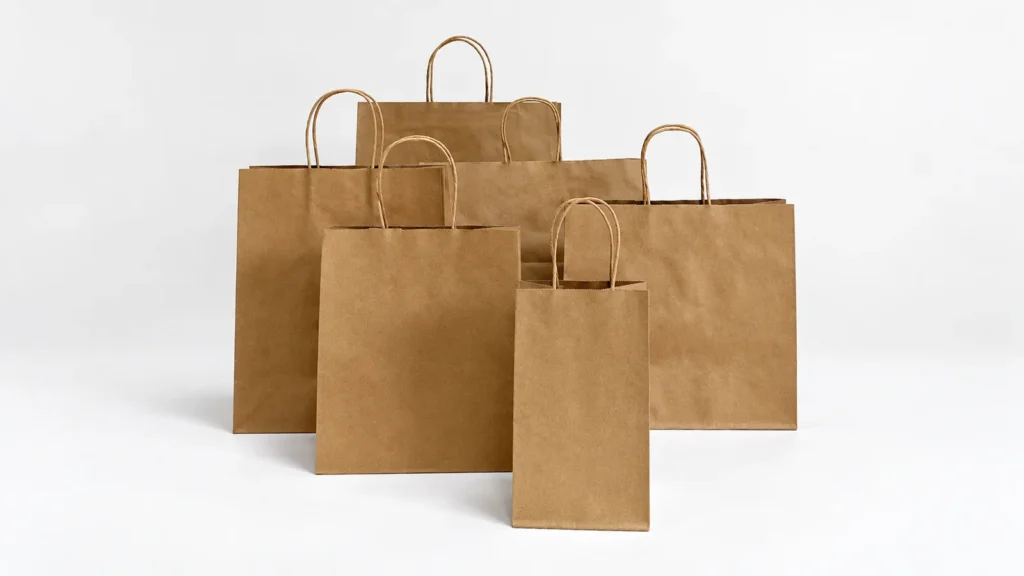 Six plain brown kraft paper bags with twisted handles arranged in different sizes and proportions.