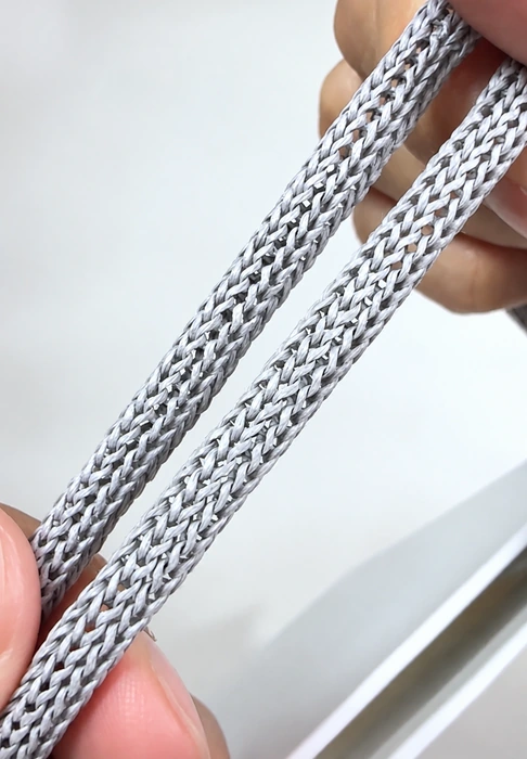 Close-up of two gray Apple bag handles showing their repeating knitted surface