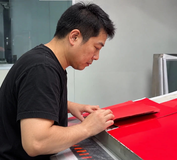 Close view of a man folding a red paper bag sample by hand