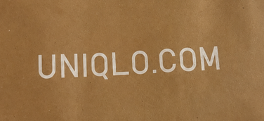 Detail of the soft white UNIQLO.COM logo against brown kraft paper