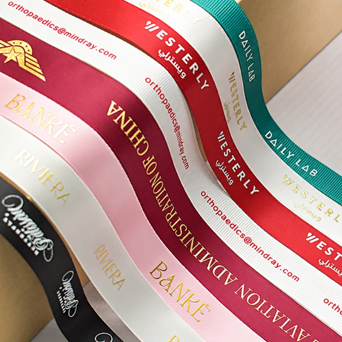 Curved ribbon samples in red, green, white, pink and black display contrasting printed brand names and logos.
