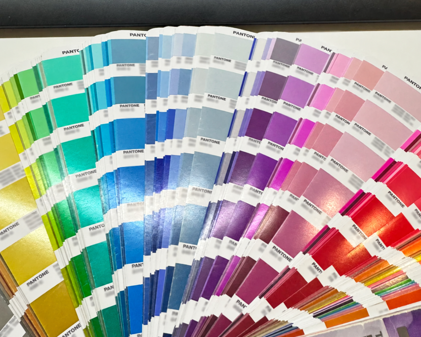 An open fan of physical Pantone colour swatches with white label bands