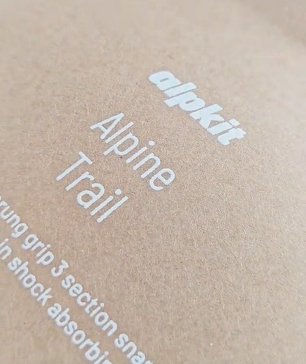 Close view of white alpkit and Alpine Trail lettering on brown kraft paper