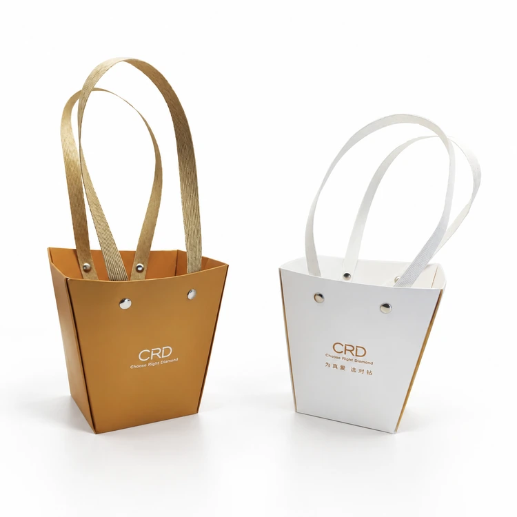 Gold-toned and white tapered paper bags with flat loop handles and visible metal rivets
