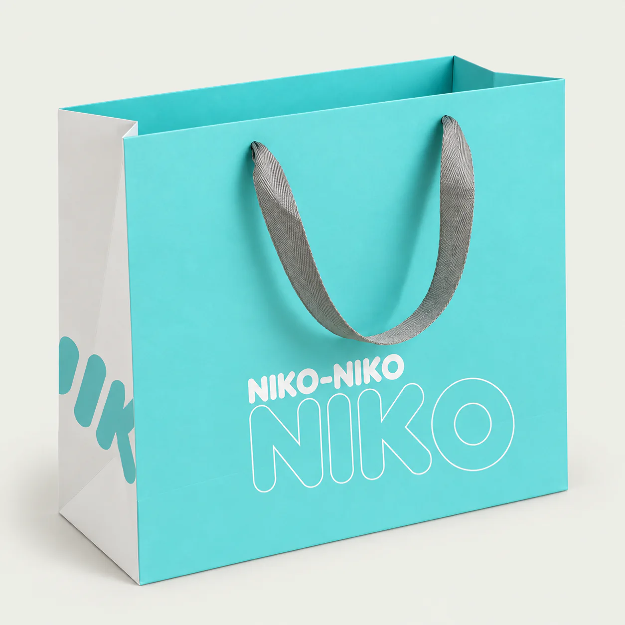 Turquoise custom paper bag with grey ribbon handles threaded through the bag.